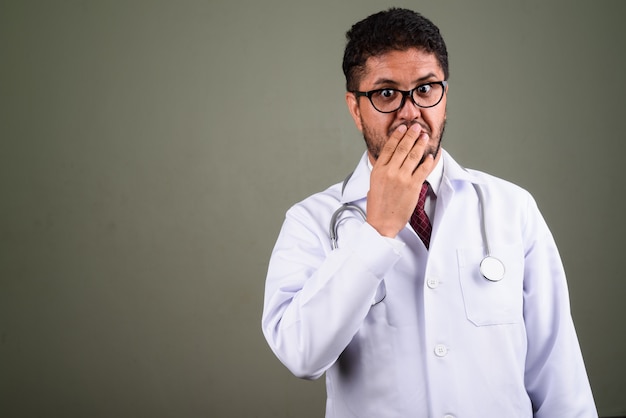 Studio shot di uomo barbuto medico contro colorato