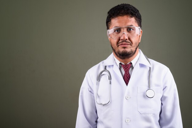 Studio shot di uomo barbuto medico indossando occhiali protettivi contro colorati