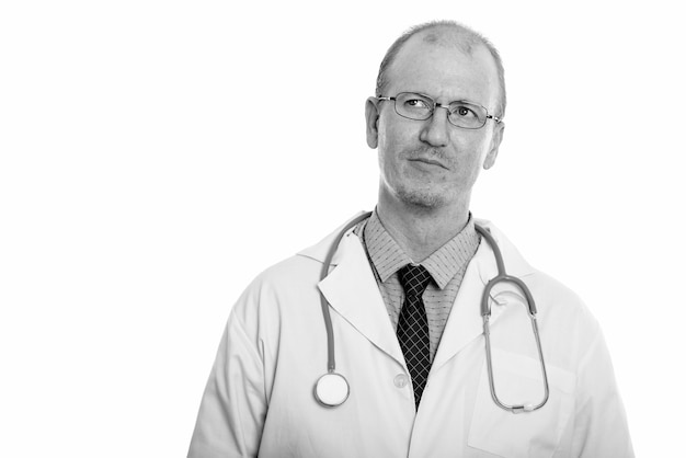 Studio shot di uomo calvo medico con barba stoppia isolato su sfondo bianco in bianco e nero