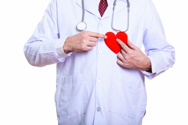 Studio shot di uomo maturo medico tenendo il cuore rosso contro il petto