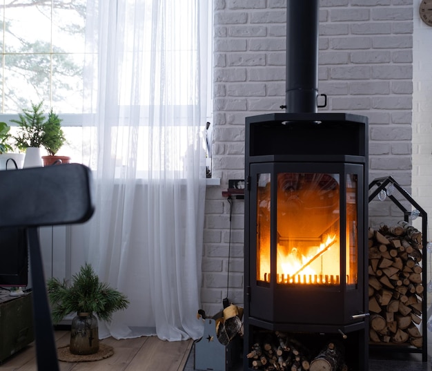 Stufa nera caminetto all'interno della casa in stile loft Riscaldamento alternativo ed ecologico stanza calda e accogliente a casa che brucia legna