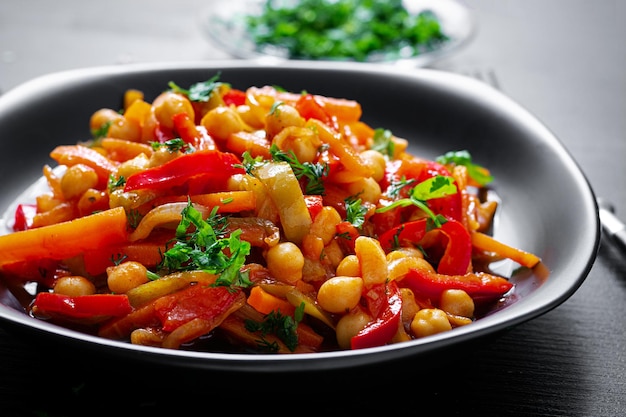 Stufato di verdure di ceci carota peperoni cipolle aglio e salsa di pomodoro al limone sul tavolo scuro Cucina orientale