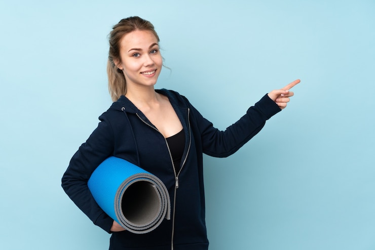 Foto stuoia della holding della ragazza dell'adolescente isolata sul dito puntato blu al lato