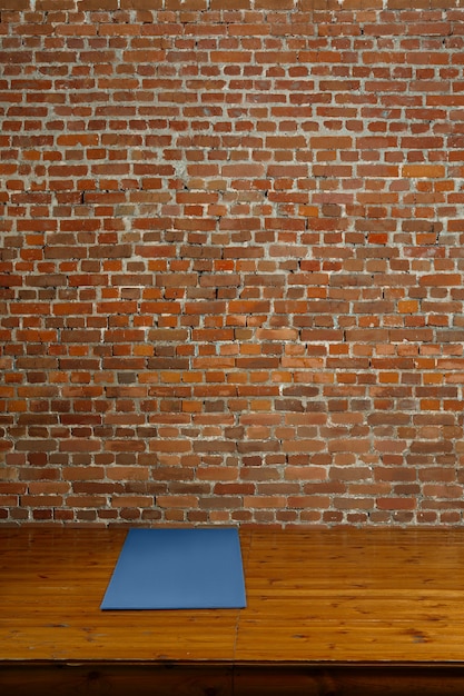 Stuoia della palestra sul podio di legno con il muro di mattoni su fondo