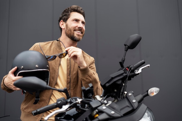 Stylish sorridente uomo sicuro motociclista che indossa casco in piedi vicino motocicletta sportiva