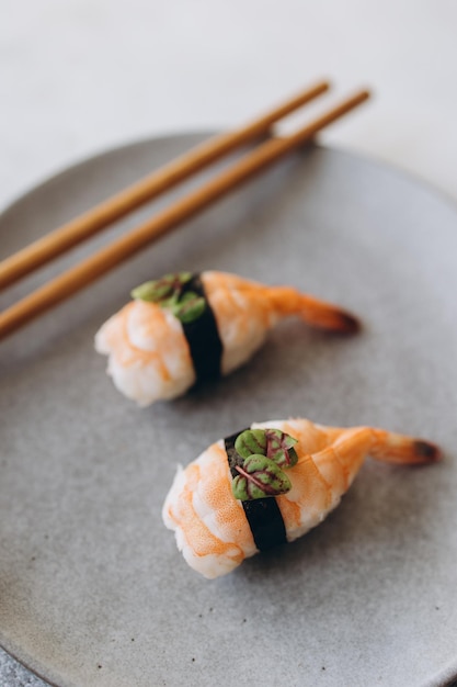 Su un piatto grigio sushi con gamberetti e bastoncini di bambù sparati dall'alto