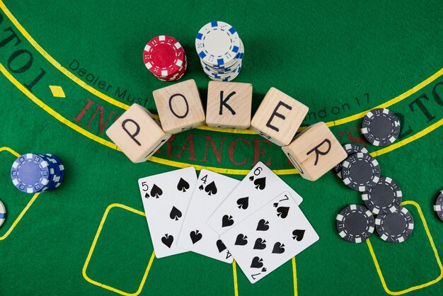 Su un tavolo da poker verde ci sono i gettoni delle carte e l'iscrizione poker su cubi di legno Concetto di poker