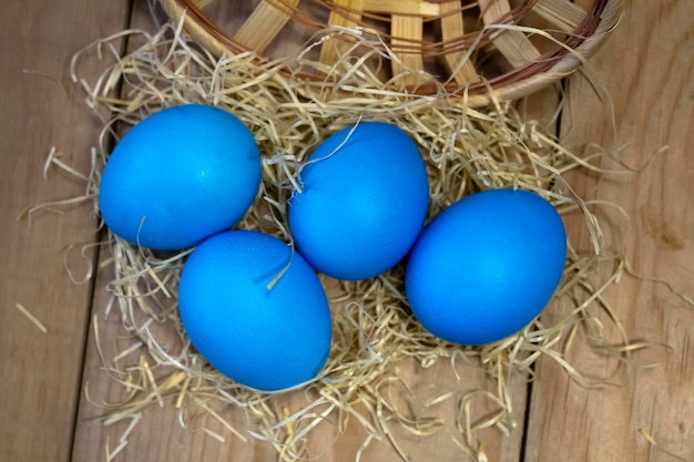 Su un tavolo di legno colorate le uova di Pasqua in un nido di paglia Concetto di Pasqua e religione