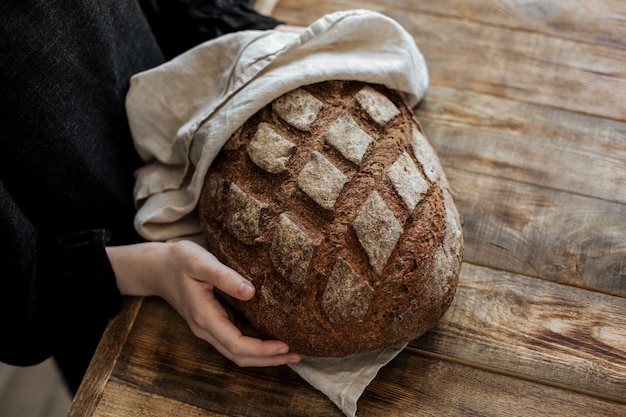 Su un tavolo di legno pane di segale nelle mani di un piccolo fornaio.