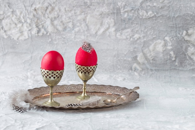Su un vassoio d&#39;argento su una bancarella ci sono due uova rosse, un cucchiaio e piume - una Pasqua ancora in vita.