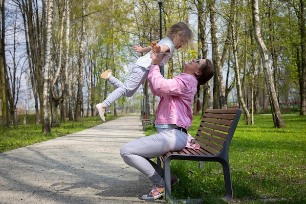 Su una panchina in un parco cittadino una madre solleva il bambino in alto in aria