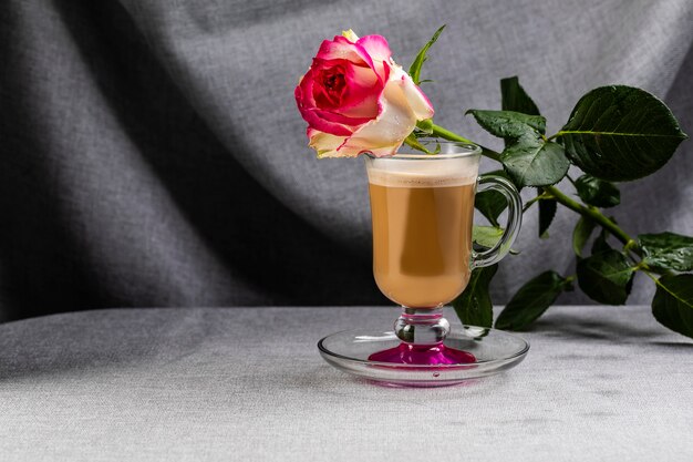 Su una tazza con una bevanda al caffè e una magnifica rosa