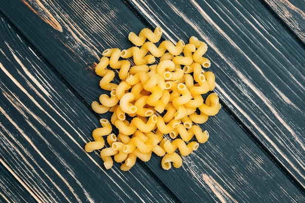 Su uno sfondo di legno nero maccheroni Un grappolo di pasta