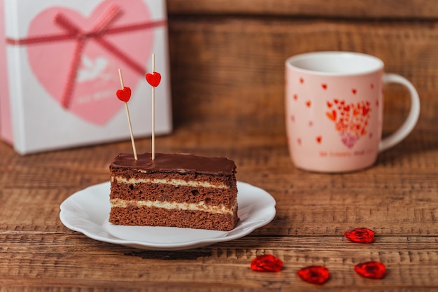 Su uno sfondo di legno, un dolce festivo con tè e una scatola di souvenir per un regalo