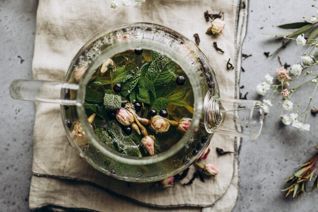 Su uno sfondo grigio ripresa dall'alto di una teiera aperta con tisane e fiori di rosa essiccati