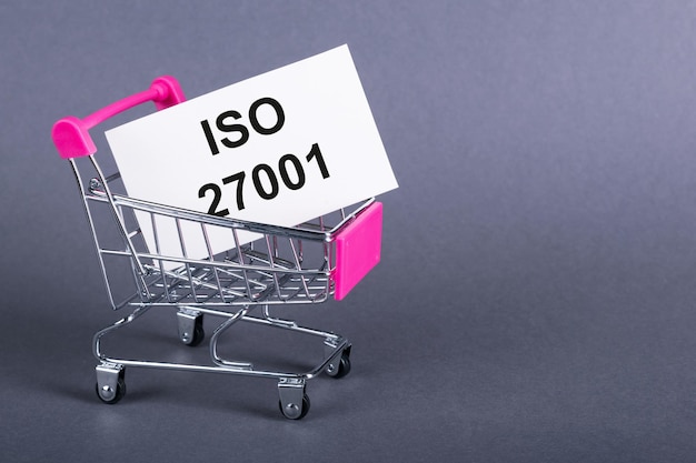 Su uno sfondo grigio un carrello della spesa una carta con la parola ISO 27001