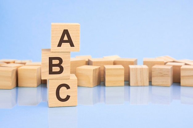 Su uno sfondo lilla chiaro brillante, blocchi e cubi di legno chiaro con il testo ABC cubes viene riflesso dalla superficie ABC abbreviazione di Always Be Closing