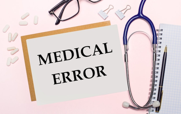 Su uno sfondo rosa chiaro, uno stetoscopio, pillole bianche e fermagli per carta, occhiali con cornici nere e un foglio di carta con il testo ERRORE MEDICO.