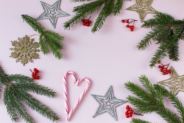 su uno sfondo rosa, rami di abete rosso, decorazioni festive (stelle, fiocchi di neve)