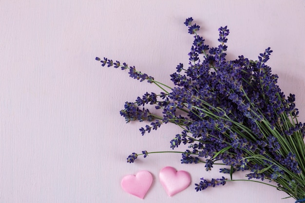 su uno sfondo rosa un bouquet di lavanda e due cuori rosa satinati