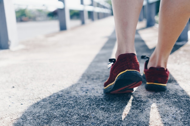 Su uno sfondo verde, una donna cammina e corre indossando scarpe da corsa. L'esercizio per la salute è una nozione.