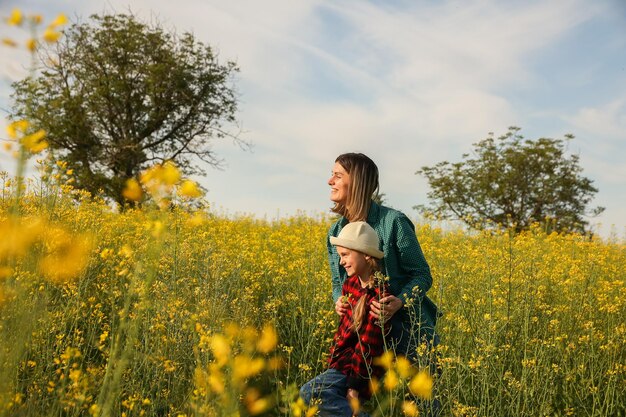 Sua madre e sua figlia coltivano la famiglia nel campo di colza indicando il campo agricolo con