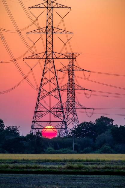 Substazione di pilastro elettrico in terreni agricoli con grande tramonto rosso per lo sfondo tecnologico