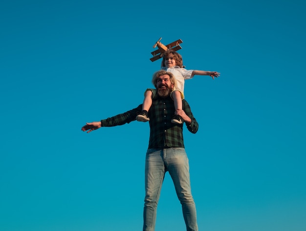 Successo e concetto di leader del bambino. Padre e figlio che giocano con l'aereo giocattolo all'aperto. Vacanza in famiglia, genitorialità. Festa del papà.