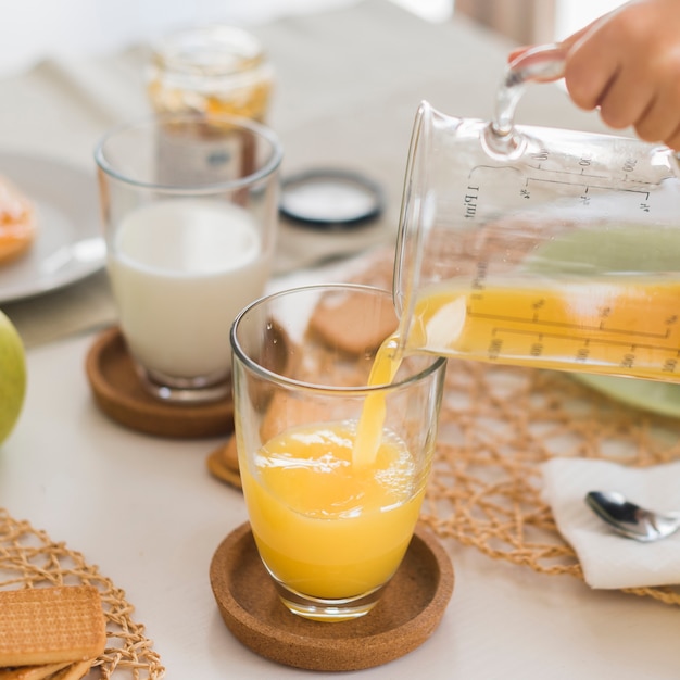 Succo d'arancia di versamento del bambino dell'angolo alto in vetro