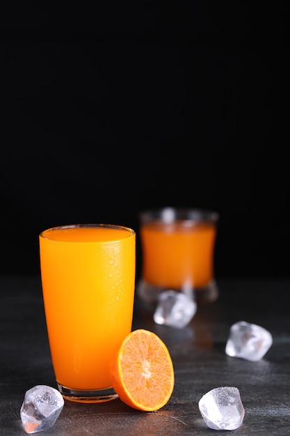Succo d'arancia fresco in vetro con ghiaccio sulla tavola di legno d'epoca.
