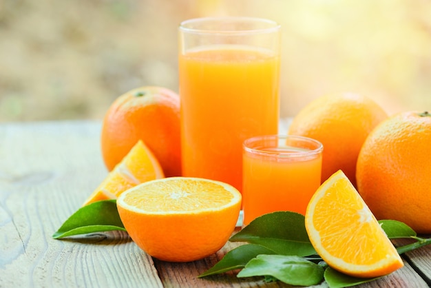Succo d'arancia fresco nel bicchiere con frutta arancione su frutta sana in legno e fetta d'arancia