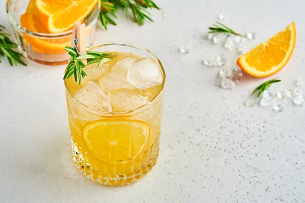 Succo d'arancia o cocktail con rosmarino e arancia con ghiaccio in vetro, limonata estiva fredda