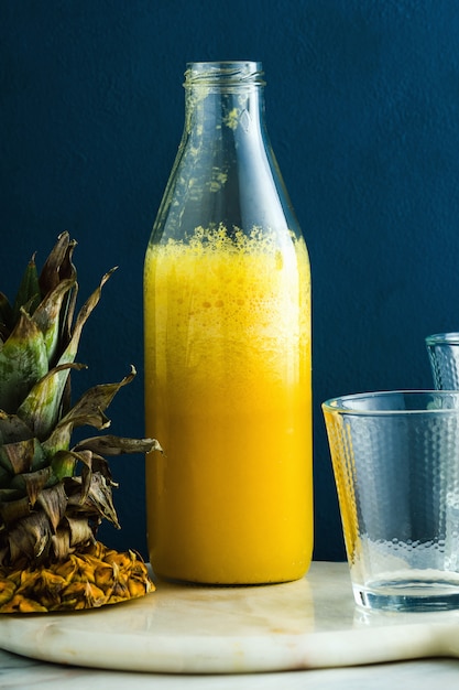 Succo di ananas fresco su un tavolo in una bottiglia e bicchieri