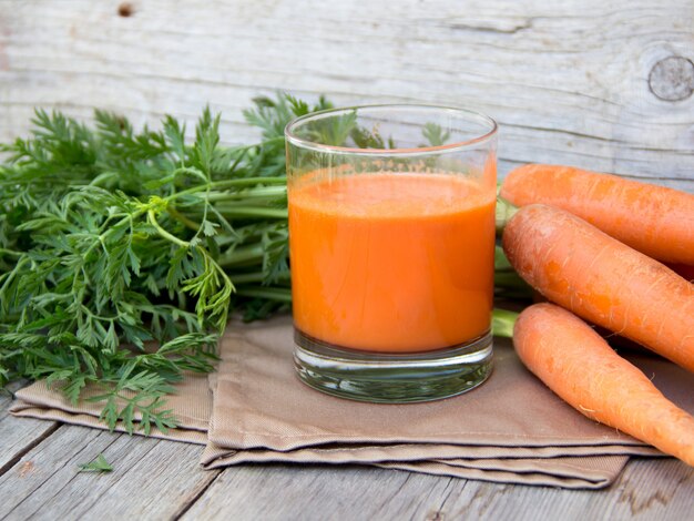 Succo di carota fresco su una fine di legno della tavola su