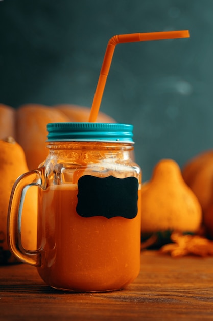 Succo di carota in bottiglia con spazio copia bicchiere di succo di verdura posto su un tavolo vicino alle zucche...