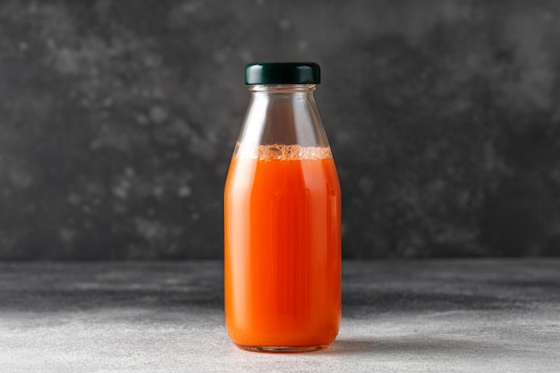 Succo di carota in bottiglia di vetro Succo appena spremuto su sfondo scuro Mock up copy space