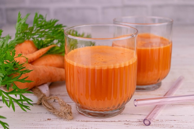 Succo di carota vitaminico fresco in un bicchiere su sfondo bianco.