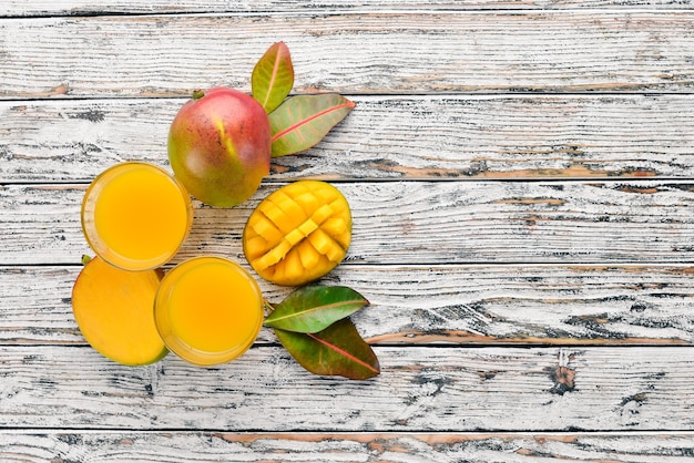 Succo di frutta di mango e mango Su uno sfondo di legno bianco Frutti tropicali Vista dall'alto Spazio libero per la copia