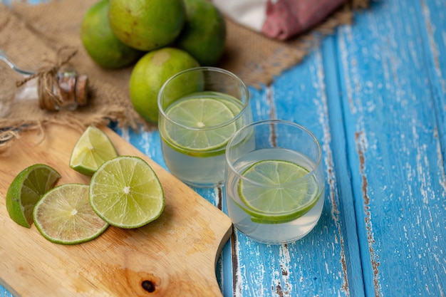 Succo di lime e limone su un tavolo di legno blu