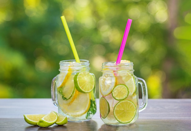 Succo di limone e lime appena spremuto con fette e cubetti di ghiaccio con un tubo in un bicchiere di vetro