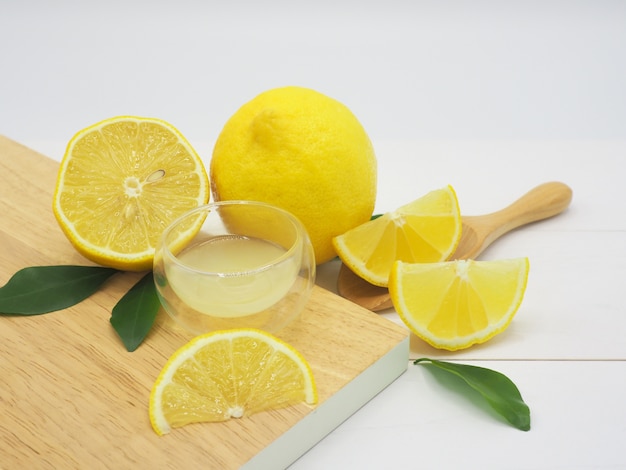 Succo di limone fresco in una piccola ciotola e fetta di limone su fondo di legno bianco