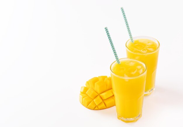 Succo di mango tropicale fresco con bella polpa tagliata a dadini e paglia di carta a strisce isolata su sfondo bianco tavolo primo piano ritagliato percorso di ritaglio