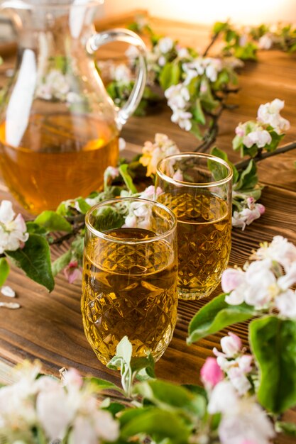 Succo di mela in un bicchiere con fiori di mela sul tavolo