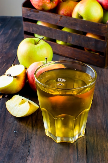 Succo di mela in un bicchiere e mele mature su un tavolo di legno