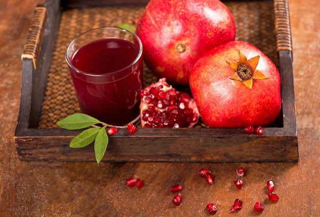 Succo di melograno e frutti di melograno su uno sfondo di legno