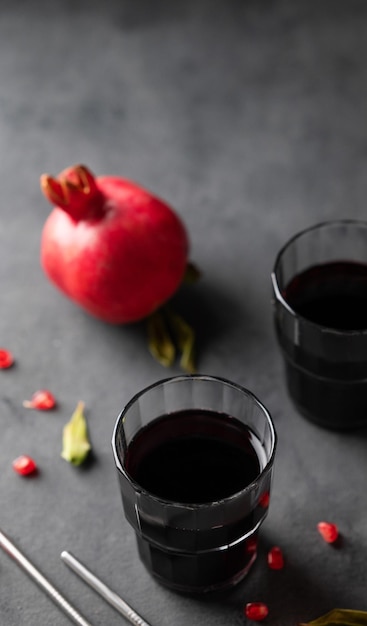 Succo di melograno naturale in un bicchiere su uno sfondo scuro con frutta fresca Una bevanda sana appena spremuta con vitamine e antiossidanti