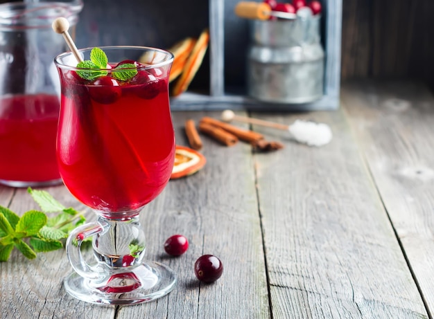 Succo di mirtillo rosso fresco con cannella e anice in vasetti di vetro sullo sfondo di legno vecchio. Messa a fuoco selettiva.