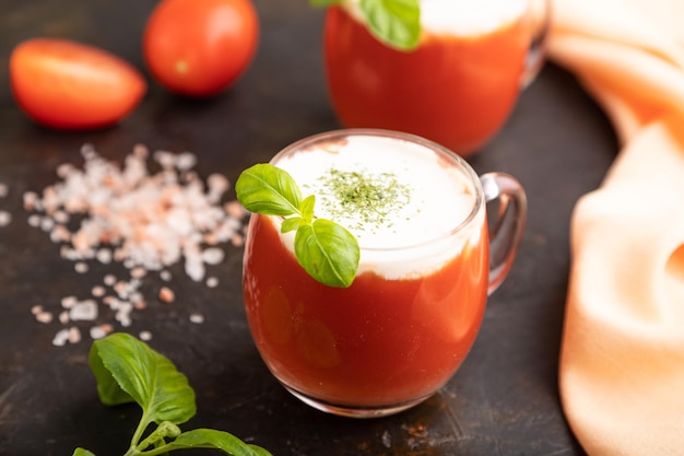 Succo di pomodoro con basilico e sale himalayano in vetro su sfondo nero Fuoco selettivo vista laterale