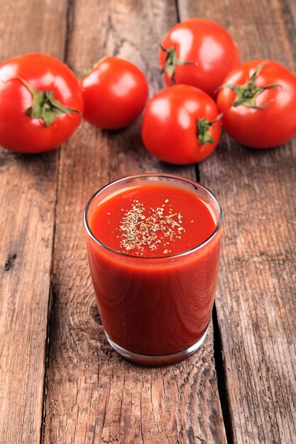 Succo di pomodoro con i pomodori rossi freschi su una tavola di legno.