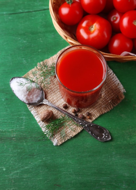 Succo di pomodoro fatto in casa in spezie di vetro e pomodori freschi su fondo di legno